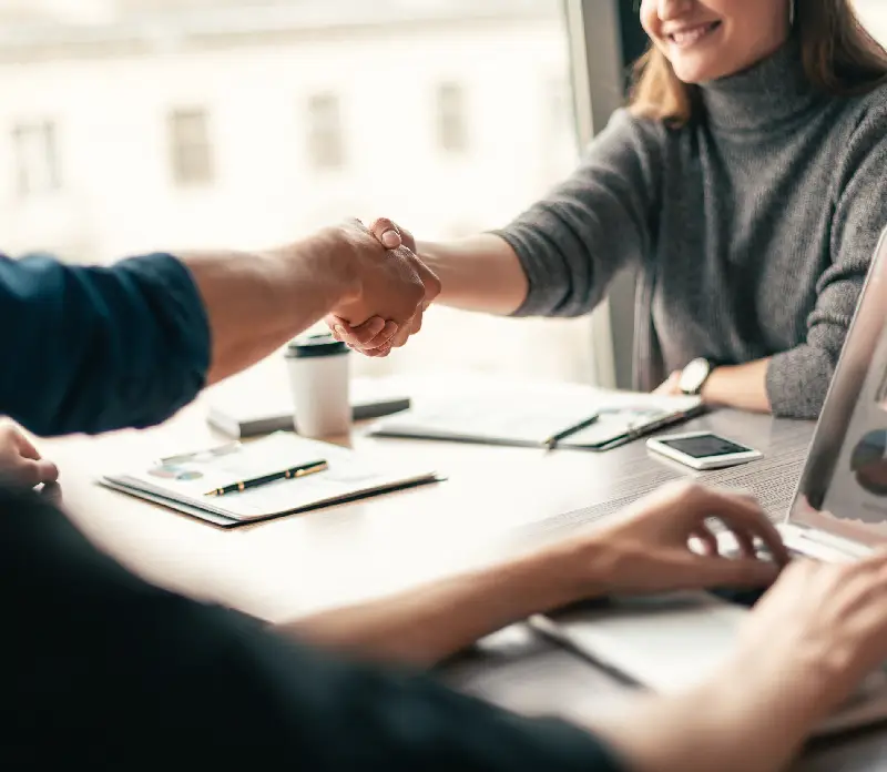 A business meeting scene featuring two people shaking hands A business meeting scene featuring two people shaking hands