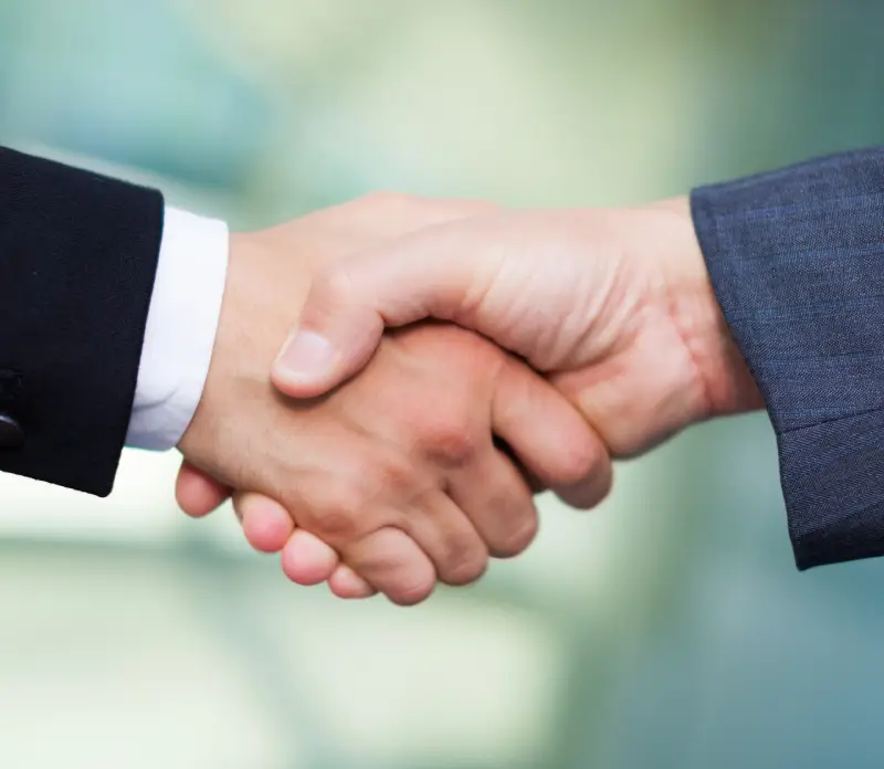Close-up of two hands shaking, one in a dark suit and the other in a light shirt Close-up of two hands shaking, one in a dark suit and the other in a light shirt