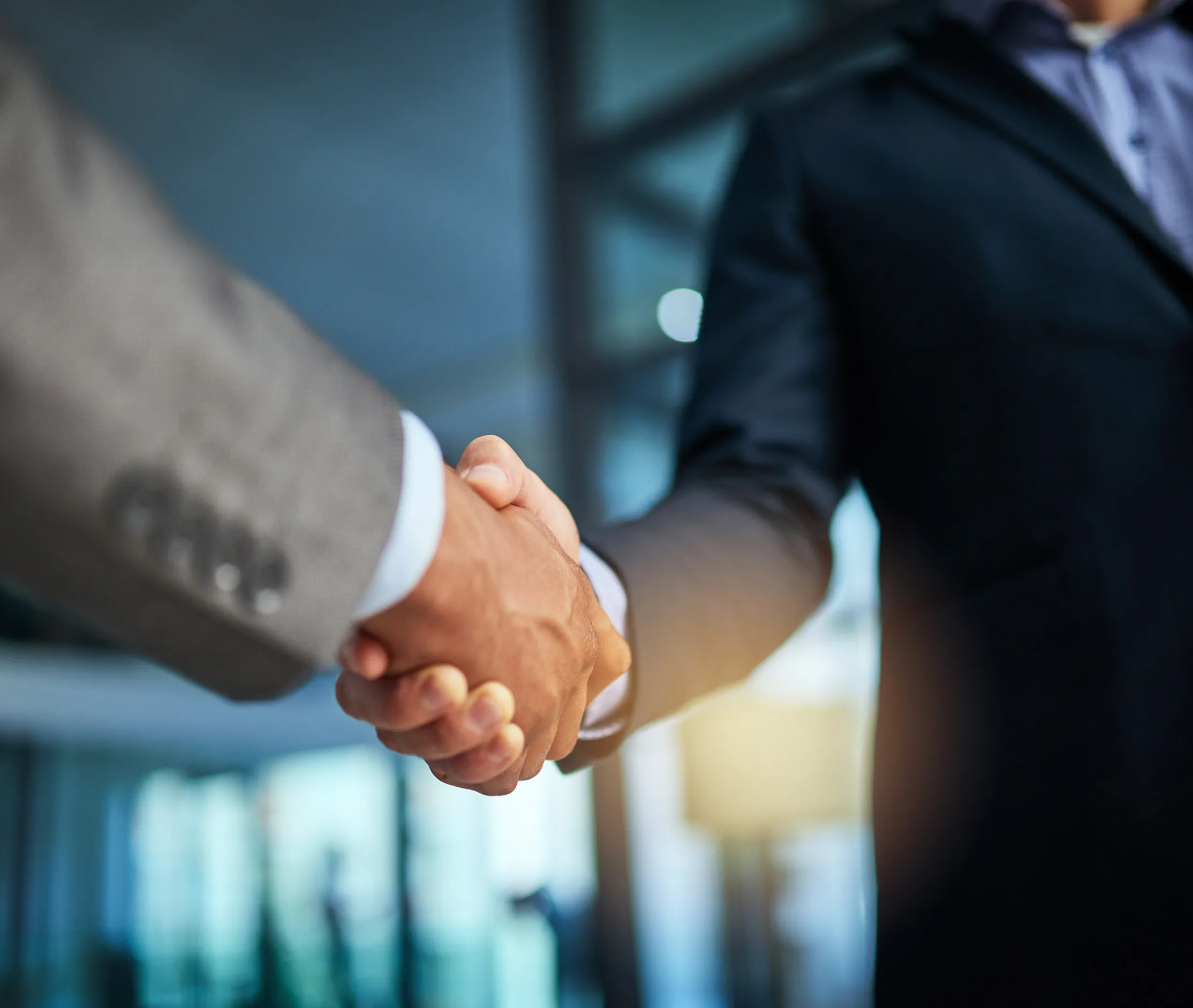 Two business professionals shake hands in a modern office setting, symbolizing agreement and partnership Two business professionals shake hands in a modern office setting, symbolizing agreement and partnership